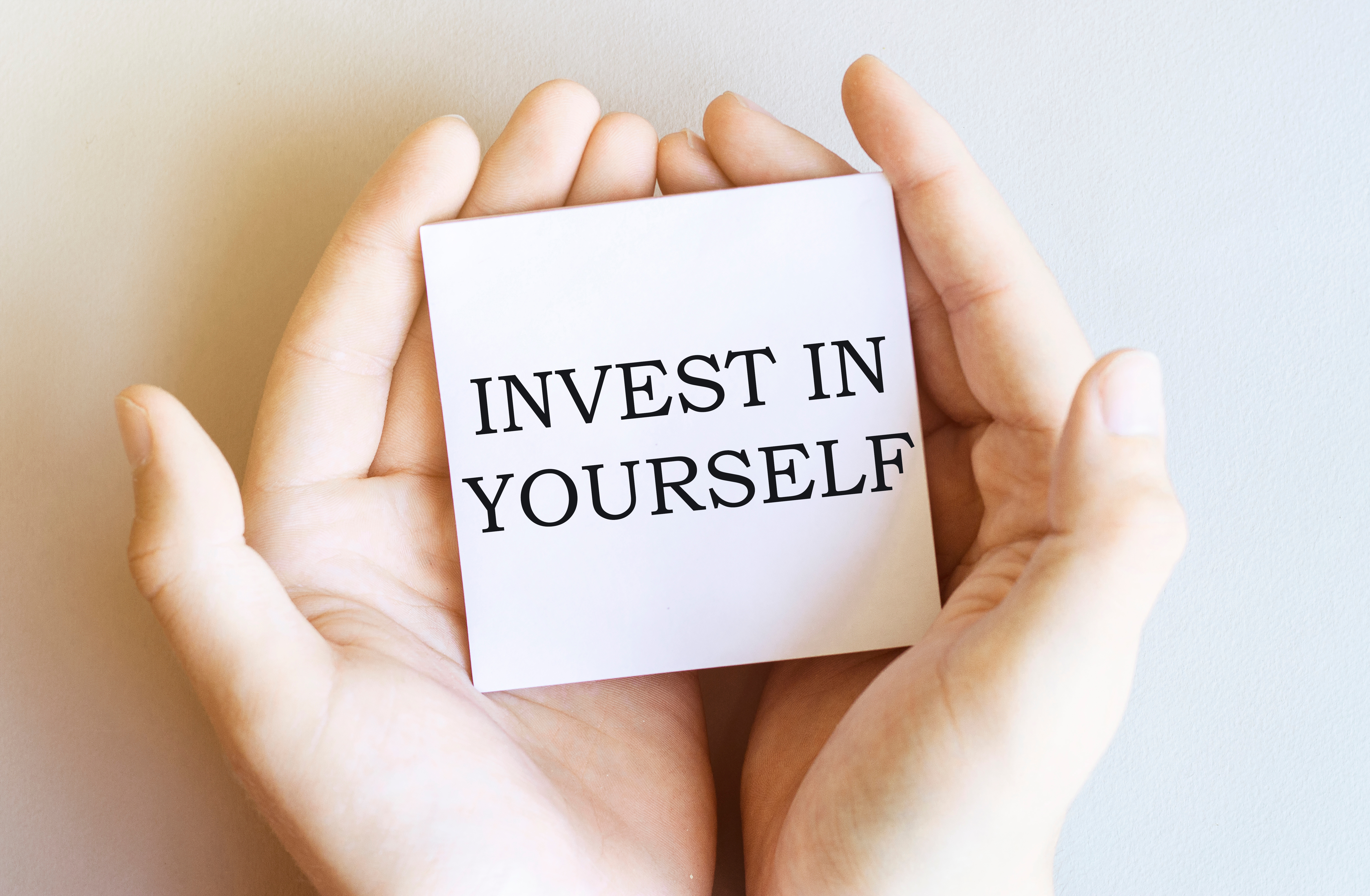 white paper with text Invest In Yourself in male hands on a white background